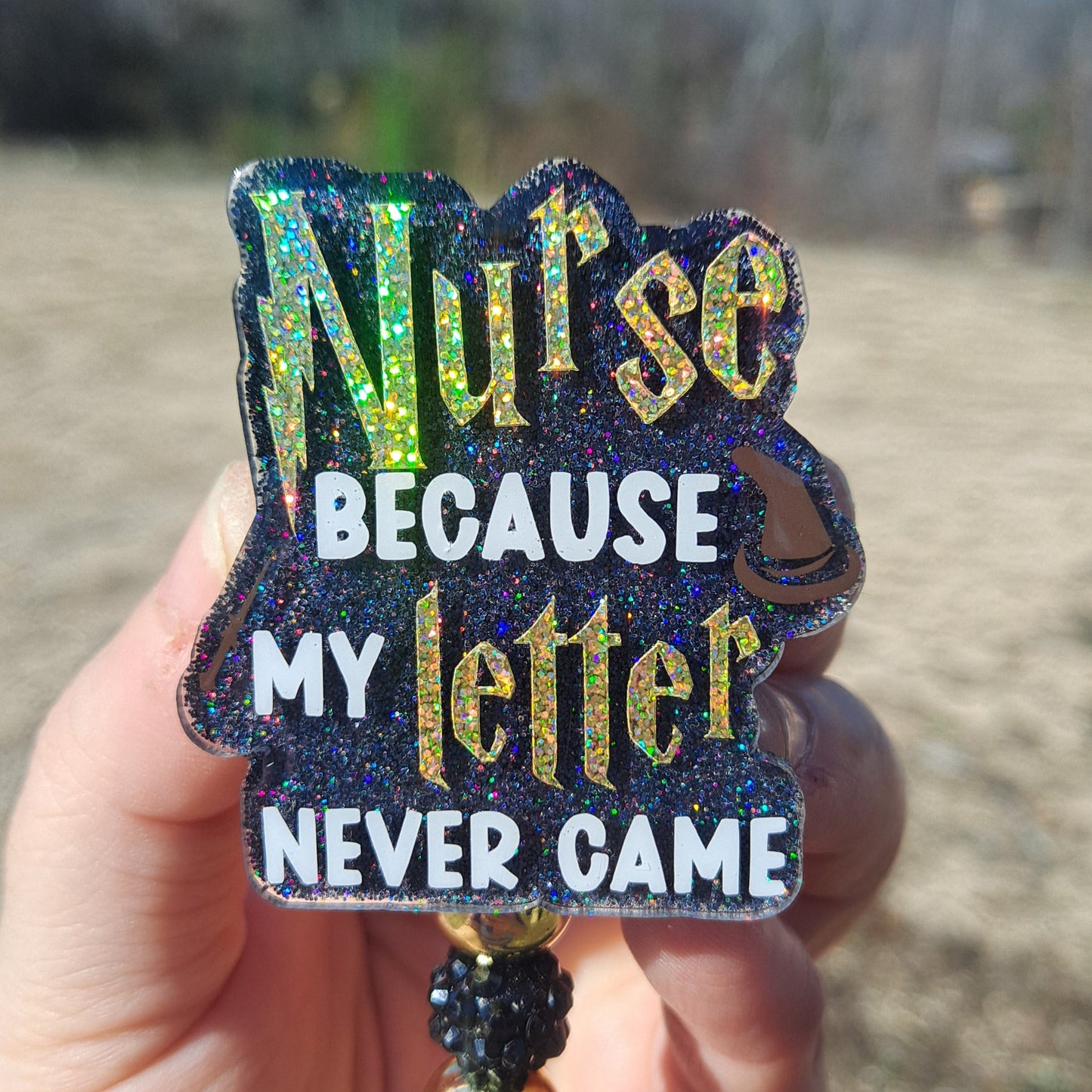 Decorative keychain with text held by a hand on a blurred background