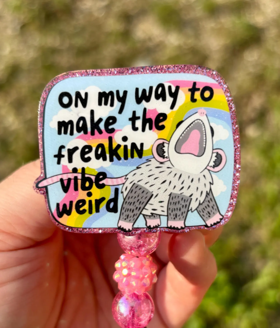 Hand holding a colorful keychain with a cartoon character and text.