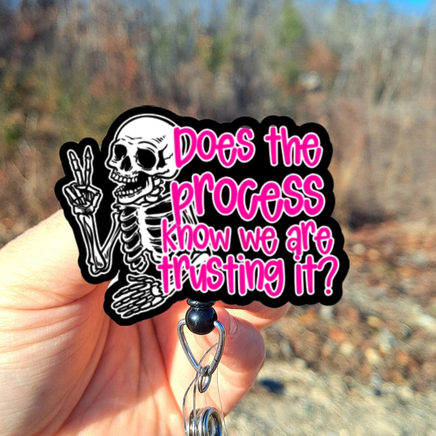 Hand holding a skeleton keychain with text against a natural background
